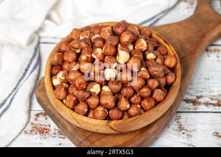 Nocciole in un recipiente di legno. Nocciola su fondo di legno bianco. Primo piano Foto Stock