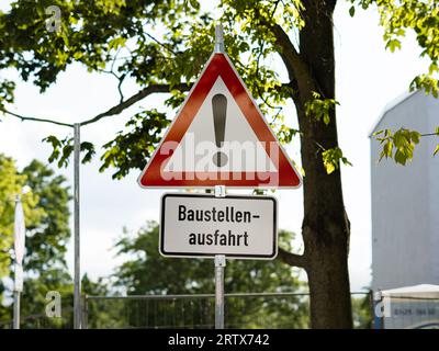 Cartello stradale tedesco di Baustellenausfahrt (uscita cantiere). Stare attenti a causa della sporcizia sulla strada e dei macchinari che attraversano la strada. Foto Stock