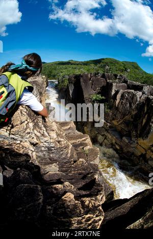 una donna escursionista gode della vista di un fiume sulla cima di una scogliera in una giornata di sole, chapada dos veadeiros, brasile Foto Stock