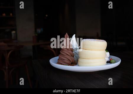 Primi piani di soffici pancake di soufflé con cioccolato e gelato alla vaniglia serviti con salsa al miele. Foto Stock