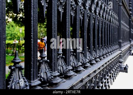 recinzione in ghisa nera. riduzione della vista prospettica. dettagli del marciapiede. persone e giardino verde visti attraverso i picchetti. parchi e all'aperto. Burggarten Foto Stock