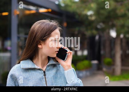 temeva una ragazza adolescente che parlava al telefono e risolveva i problemi che camminavano per strada. conferma del noleggio dell'alloggio, prenotazione dell'hotel online Foto Stock