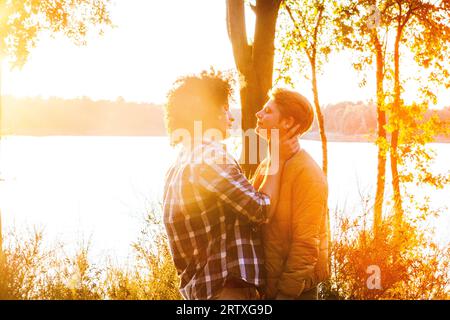 Una bella e variegata coppia, un uomo arabo e una donna caucasica, condividono un momento di cuore mentre si abbracciano contro il caldo bagliore di un romantico tramonto. Il loro amore trascende i confini, catturando l'essenza dell'unità e dell'affetto. Appassionata coppia multirazziale che abbraccia al tramonto, Love Knows No Bounds. Foto di alta qualità Foto Stock