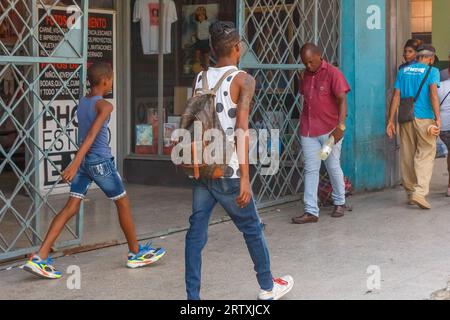 L'Avana, Cuba, 2023, i cubani camminano su un marciapiede della città. Vita cittadina e stile di vita di persone reali nell'isola caraibica Foto Stock
