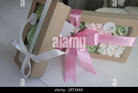 Due scatole con marshmallow. Fiori di Zephyr. Marshmallow fatti in casa in una confezione regalo di carta. La scatola è legata con un nastro legato a un arco. Etichetta per la t Foto Stock