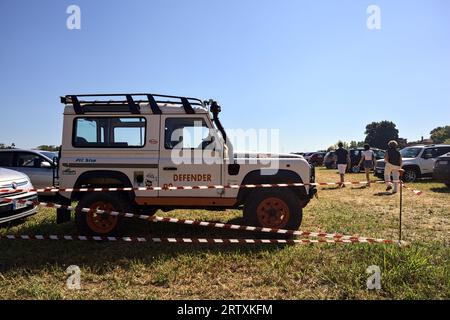 Land Rover Defender in un parcheggio su un campo falciato in una giornata di sole Foto Stock