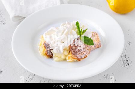 Porzione di budino di limone al forno guarnito con panna montata Foto Stock