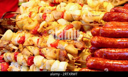 un mucchio di spiedini di carne con verdure cotte e salsicce in un chiosco di street food Foto Stock