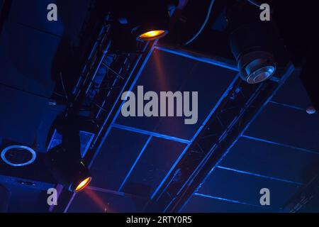 I fasci luminosi gialli si trovano su sfondo blu scuro del soffitto, apparecchiature di illuminazione del palcoscenico Foto Stock