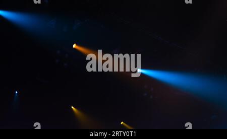 Luci spot panoramiche, fasci blu e gialli sono in fumo su sfondo scuro e illuminazione moderna del palcoscenico Foto Stock