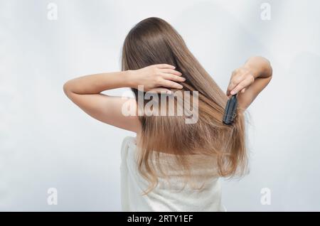 Vista posteriore di una bella donna che si pettina i capelli con la spazzola Foto Stock