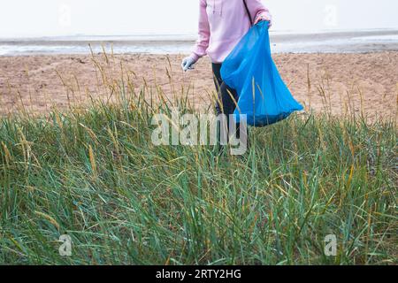 Gruppo di giovani volontari e partecipa a una giornata di pulizia del lavoro della comunità sulla spiaggia sabbiosa, attivisti che raccolgono rifiuti, rifiuti, spazzatura e spazzatura Foto Stock