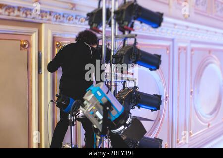 L'assistente del lavoratore di palcoscenico prepara le luci, l'ingegnere della luce, il tecnico dell'illuminazione che regola le luci per concerti e spettacoli musicali nella sala, l'installazione di una professione Foto Stock