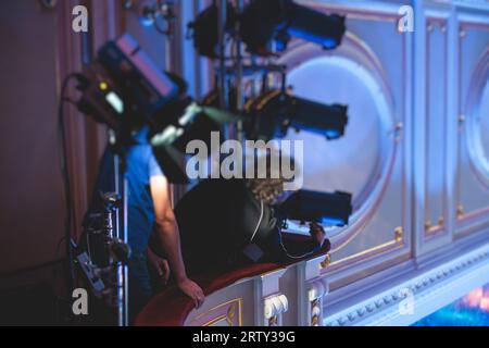 L'assistente del lavoratore di palcoscenico prepara le luci, l'ingegnere della luce, il tecnico dell'illuminazione che regola le luci per concerti e spettacoli musicali nella sala, l'installazione di una professione Foto Stock