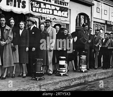 Phoenix, Arizona: c. dicembre 1937 i fan del cinema attendono in coda per entrare al Rialto Theater. Il direttore del teatro ha messo fuori le stufe a olio davanti all'edificio, rendendo così i suoi clienti abbastanza confortevoli in attesa di entrare in inverno. Foto Stock