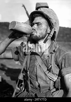 Saipan, Isole Marianne 8 luglio 1944 caldo e stanco dopo aver combattuto sulle spiagge occidentali sotto il Monte Marpi, Marine PFC T. E. Underwood of St. Petersburg, Flag., prende una lunga e fresca bevanda d'acqua dalla sua mensa. Fotografia di Stanley Troutman. Foto Stock