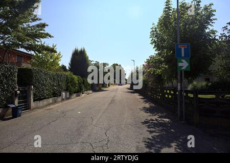 Strada delimitata da recinzioni e piante di giardini appesi fuori dalle mura di un villaggio italiano in una giornata di sole Foto Stock