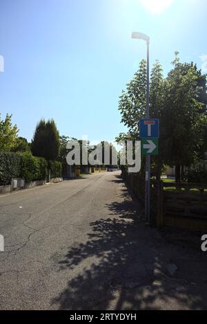 Strada delimitata da recinzioni e piante di giardini appesi fuori dalle mura di un villaggio italiano in una giornata di sole Foto Stock