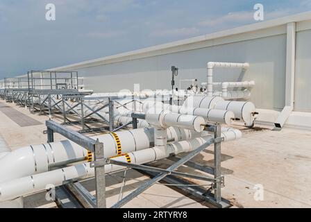 Tubazioni isolate sul tetto di un impianto di refrigerazione industriale a ciclo di ammoniaca per la conservazione a freddo. Mostra i ponti pedonali per raggiungere l'altro lato dei tubi. Foto Stock