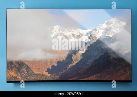 Schermo TV con paesaggio montano su una parete blu chiaro Foto Stock