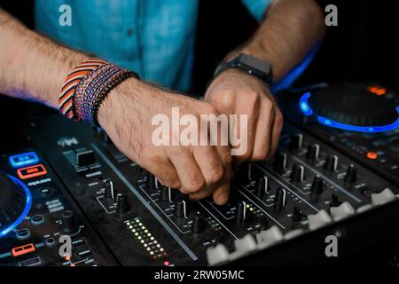 Mani da DJ che giocano con il controller delle attrezzature del club professionale, primo piano, esempio di vita notturna. Foto Stock