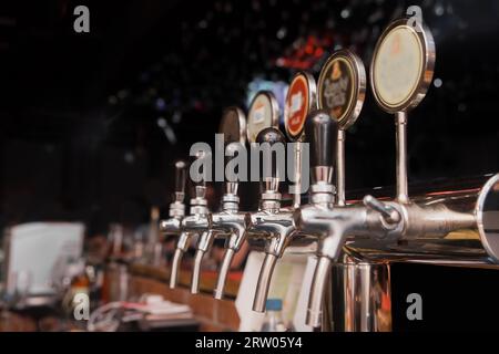 Una linea di rubinetti di birra alla spina nel bar dello stabilimento, primo piano. Foto Stock