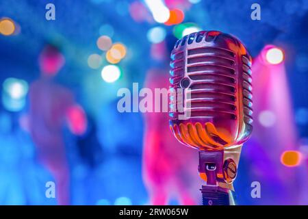 Primo piano del microfono retrò professionale in un'atmosfera da club di luci al neon. Foto Stock