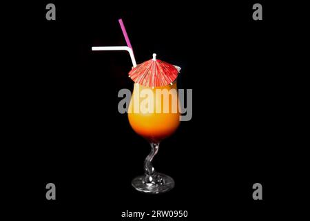 Cocktail esotico dall'aspetto tropicale con ombrellone, ottimo servizio con bicchiere da bevanda rosso-arancio paglierino su sfondo nero. Foto Stock