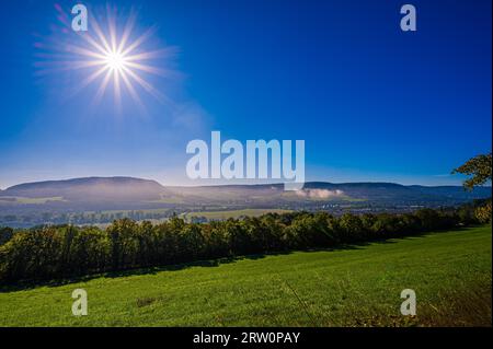 Nebbia sotto le montagne centrali sopra il villaggio di Kunitz vicino a Jena con stella solare e cielo blu, Jena, Turingia, Germania Foto Stock