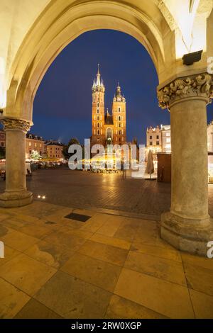 Basilica di Santa Maria di notte incorniciata da arco del panno arcade Hall a Cracovia, Polonia, chiesa gotica alla piazza principale della città vecchia Foto Stock