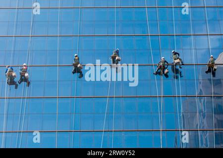 Operai pulire le finestre come un team su un grattacielo nel centro di Seoul, Corea del Sud Foto Stock