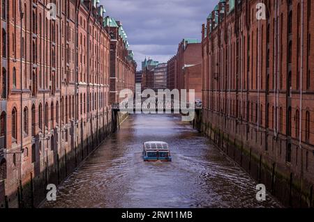 Imbarcazione turistica nel famoso Speicherstadt warehouse district con nuvole scure a Amburgo, Germania Foto Stock