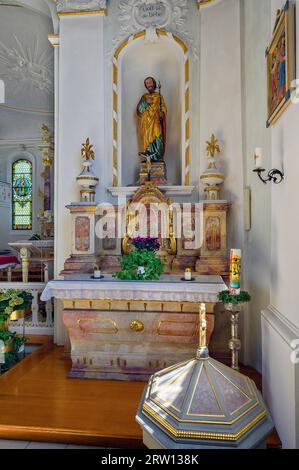 Altare laterale con figura sacra e fonte battesimale, Chiesa cattolica della Santissima Trinità, Kronburg im Illerwinkel, Baviera, Germania Foto Stock