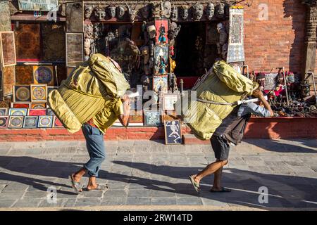 Kathmandu, Nepal, 19 ottobre 2014: Due uomini nepalesi che trasportano pacchi pesanti sulla schiena Foto Stock