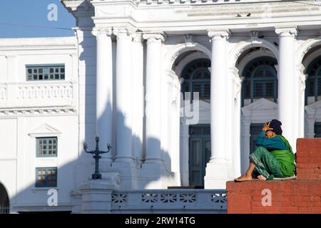 Kathmandu, Nepal, 19 ottobre 2014: Una donna anziana seduta di fronte a un tempio al Durbar Sqaure Foto Stock