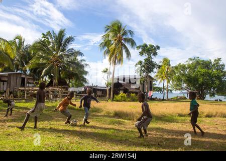 Chea Vilalge, Isole Salomone, 15 giugno 2015: Gruppo di bambini che giocano a calcio nel villaggio locale Foto Stock