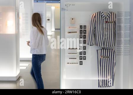 Oranienburg, Germania. 15 settembre 2023. Un visitatore passa davanti a una vetrina che mostra l'uniforme di un prigioniero nell'ex campo di concentramento di Sachsenhausen. Credito: Hannes P. Albert/dpa/Alamy Live News Foto Stock
