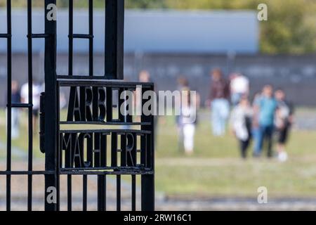 Oranienburg, Germania. 15 settembre 2023. Vista del cancello d'ingresso con l'iscrizione "Arbeit macht frei" (il lavoro ti libera); sullo sfondo, i visitatori camminano attraverso i terreni dell'ex campo di concentramento di Sachsenhausen. Credito: Hannes P. Albert/dpa/Alamy Live News Foto Stock