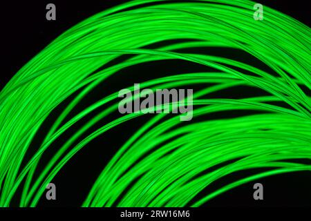 Foto luminose e insolite di sottili fili luminosi, lime, giallo, verde bruciato al buio. Foto Stock