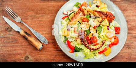 Gustosa insalata di verdure fresche e tentacoli di polpo. Insalata di polpo su fondo di legno. Foto Stock