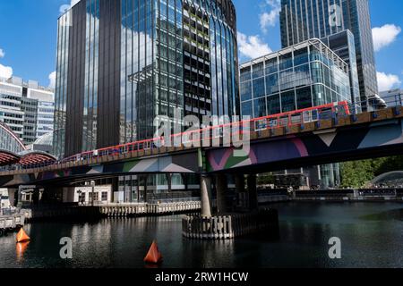 Il treno DLR sui binari sopraelevati attraversa Middle Dock verso la stazione di Canary Wharf nel cuore del quartiere finanziario di Canary Wharf il 15 agosto 2023 a Londra, Regno Unito. Canary Wharf è un'area situata vicino all'Isle of Dogs nel London Borough of Tower Hamlets ed è definita dalla Greater London Authority come parte del quartiere centrale degli affari di Londra. Insieme alla City of London, costituisce uno dei principali centri finanziari del Regno Unito e del mondo, contenente molti grattacieli tra cui il terzo più alto del Regno Unito, One Canada Square. La Docklands Light Rail Foto Stock