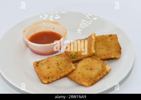 Ravioli fritti con salsa rossa su un piatto bianco Foto Stock