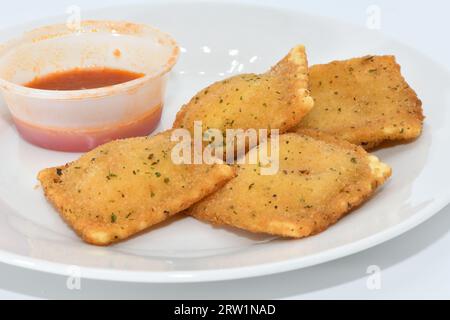 Ravioli fritti con salsa rossa su un piatto bianco Foto Stock