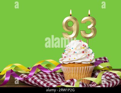 Torta di compleanno con candela numero 93 - su sfondo verde. Foto Stock