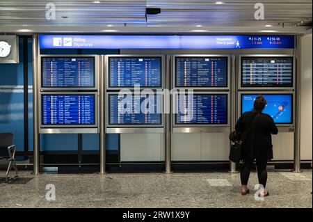 04.08.2023, Germania, Assia, Francoforte - Europa - un viaggiatore aereo guarda gli schermi di un tabellone con le informazioni di volo per le partenze in T Foto Stock