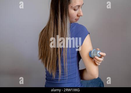 Ragazza che applica il cerotto di monitoraggio del glucosio flash sul braccio Foto Stock