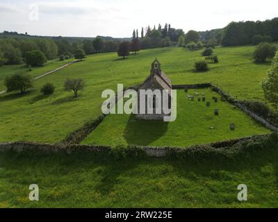 Una vista aerea della chiesa di St Oswald a Widford in un lussureggiante cielo verde e blu Foto Stock