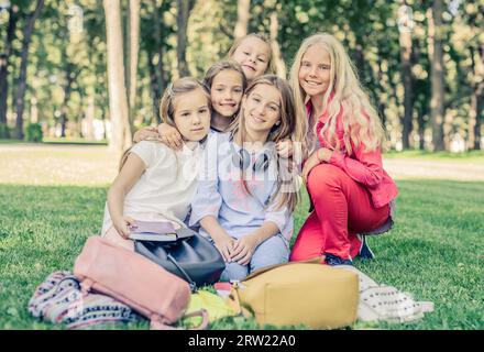 Le bambine sorridenti si siedono insieme abbracciando l'erba nel parco Foto Stock