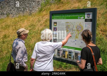 26.06.2023, Germania, Assia, Amoeneburg - i turisti camminano lungo il circuito del muro, guardano un cartello informativo, una mappa. Amoeneburg è una piccola città della M Foto Stock