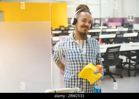 Il detergente stanco nei guanti protettivi si tiene sulla schiena Foto Stock